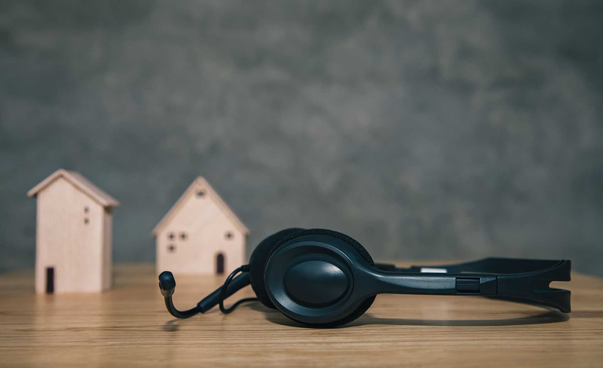 A black headset on a table infront of miniature wooden houses.